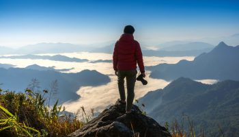 Photographer hand holding camera and standing on top of the rock Photographer hand holding camera and standing on top of the rock